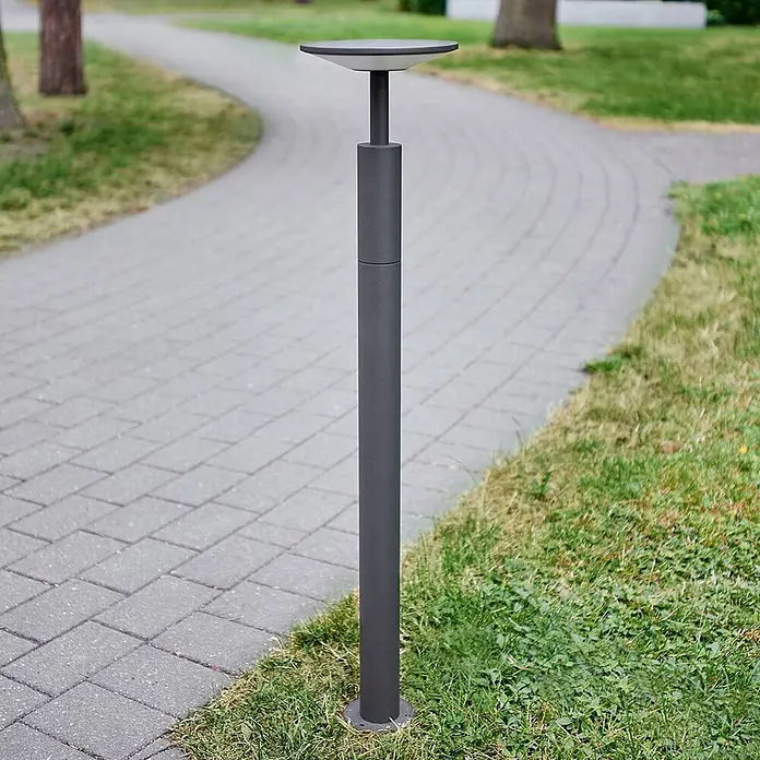 Lucande LED Wegeleuchte anthrazit Gartenlampe 100cm Pollerleuchte Aluminium -  - Hohe, dunkelgraue zylindrische Gartenleuchte mit flacher runder Oberseite, die einen gepflasterten Weg beleuchtet.