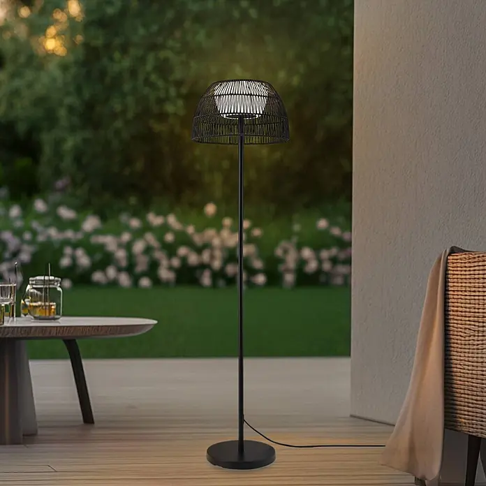 Lucande LED Stehlampe Outdoor in schwarz, Stehleuchte Garten -  - Schwarze Outdoor-Stehlampe mit geflochtenem Rattan-Schirm, beleuchtet eine Terrasse.