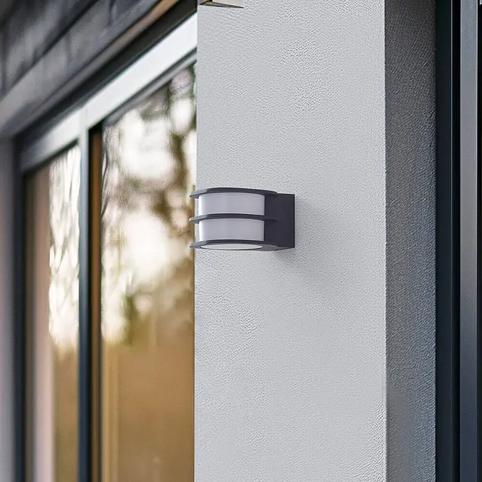 Lindby Außenwandleuchte Fyra - alu / grau / zink, weiß / opal, IP54 - Dunkelgraue Außenwandleuchte mit weißen Diffusoren, an einer strukturierten Wand neben einem Fenster montiert.