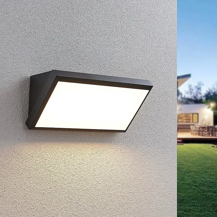 Lindby LED Wandleuchte aussen in dunkelgrau, weiß, Aussenlampe Wand -  - Rechteckige, abgewinkelte anthrazitfarbene Außenwandleuchte, strahlt helles Licht auf eine strukturierte Wand im Außenbereich.