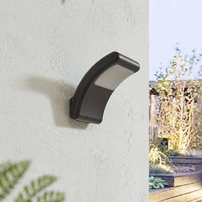 Lindby LED Wandleuchte innen in dunkelgrau, weiß, Wandstrahler -  - Gekrümmte dunkelgraue Außenwandleuchte mit weißem Diffusor, an strukturierter Wand montiert.