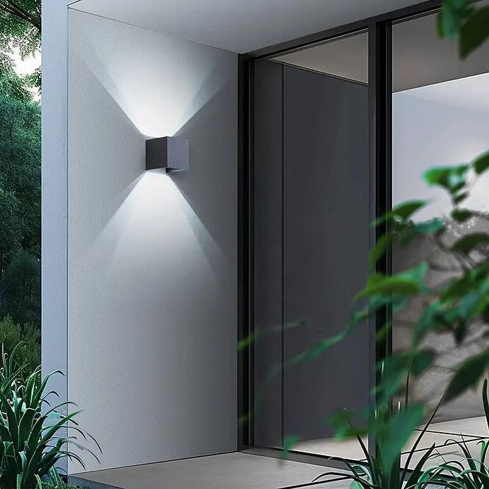 Lindby LED Wandleuchte aussen Smart Home in dunkelgrau, dimmbar up down -  - Graue würfelförmige Außenwandleuchte an einer Wand, wirft Licht nach oben und unten.