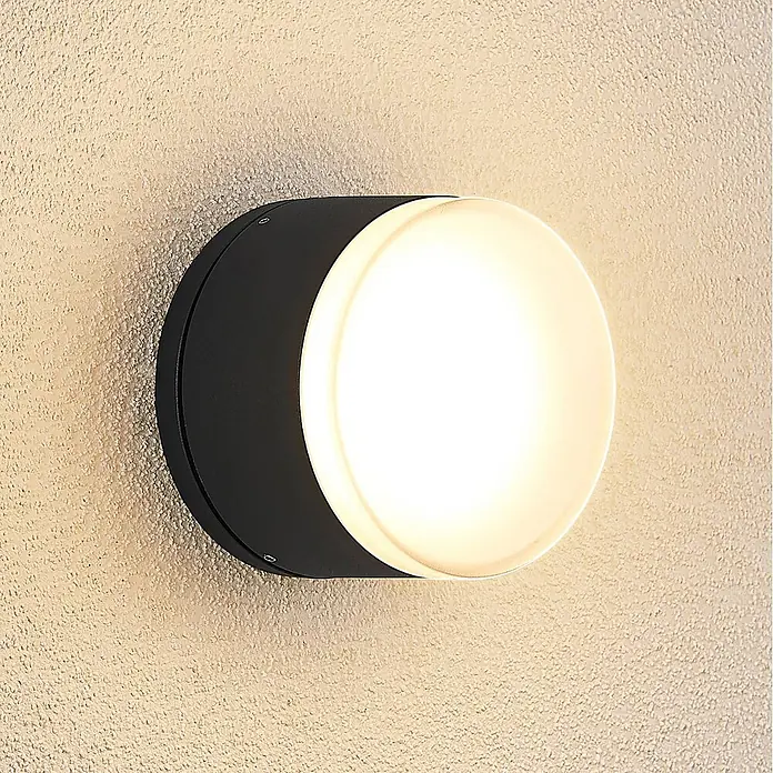 Lindby LED Wandleuchte aussen in dunkelgrau, weiß, Aussenlampe Wand -  - Runde schwarze Wandleuchte mit warmweißem Licht an strukturierter Wand montiert.