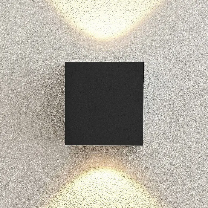 Arcchio LED Wandleuchte aussen in anthrazit, Aussenlampe Wand -  - Schwarze quadratische Wandleuchte, die Licht nach oben und unten auf eine strukturierte Wand wirft.