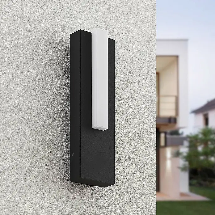 Lucande LED Wandleuchte aussen in anthrazit, weiß, Aussenlampe Wand -  - Rechteckige schwarze Außenwandleuchte mit vertikalem weißem Lichtdiffusor, an einer texturierten Außenwand eines modernen Hauses montiert.