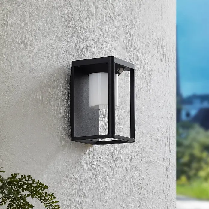 Lucande Außenwandleuchte Tilena - schwarz, IP54 - Schwarze rechteckige Außenwandleuchte mit weißem Diffusor und Bewegungssensor, an einer strukturierten weißen Wand.