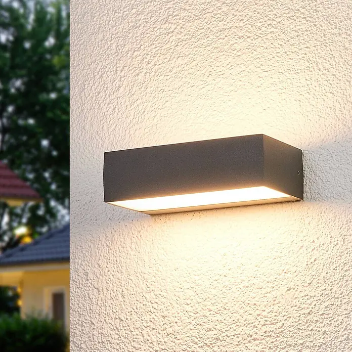 Lucande LED Wandleuchte aussen in weiß, dunkelgrau, Aussenlampe Wand -  - Eine rechteckige, anthrazitfarbene Außenwandleuchte an einer strukturierten Wand, die warmweißes Licht nach oben und unten abgibt.