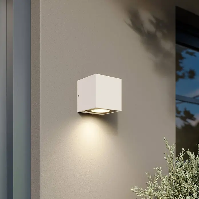 Arcchio LED Wandleuchte aussen in weiß, Aussenlampe Wand -  - Weiße kubische Außenwandleuchte an einer Wand, die warmes Licht nach unten abgibt.