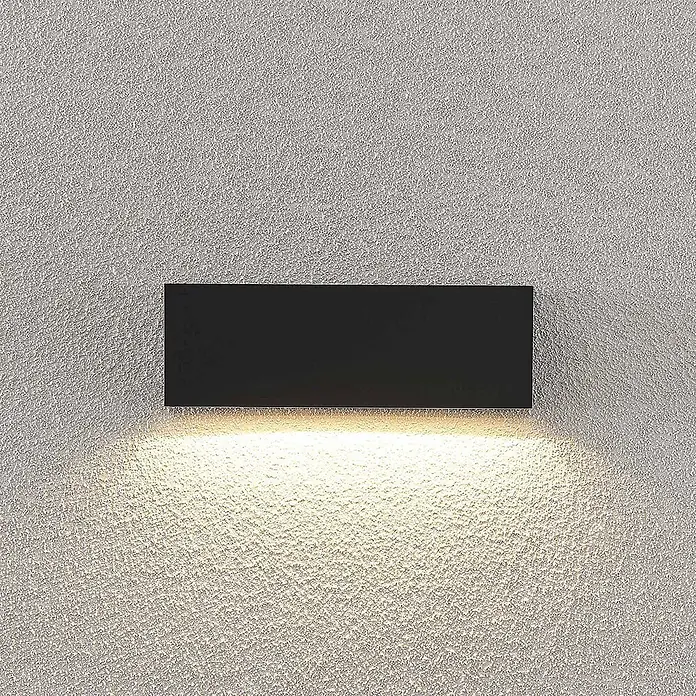Lindby LED Wandleuchte aussen in dunkelgrau, Aussenlampe Wand -  - Rechteckige schwarze Wandleuchte wirft warmes Licht nach unten auf eine strukturierte Wand.