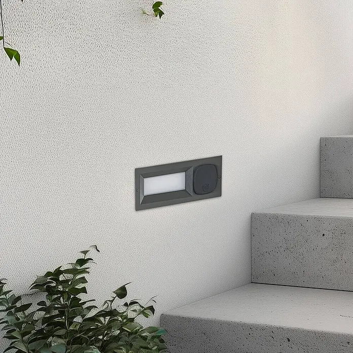 Lucande Außenwandleuchte Lachlain - schwarz, IP54 - Dunkelgraue Outdoor-Stufenleuchte mit integriertem Bewegungssensor und Leuchtfläche an der Wand montiert.