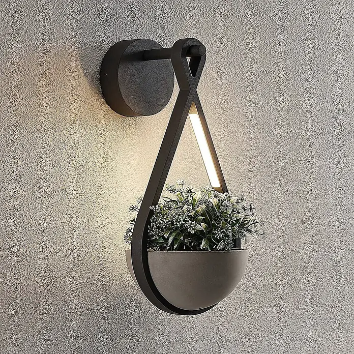 Lucande LED Wandleuchte aussen in dunkelgrau, Aussenlampe Wand -  - Dunkelgraue Wandleuchte mit integriertem Pflanzgefäß und LED-Beleuchtung, montiert an einer strukturierten Wand, mit kleiner Pflanze in grauer Schale.