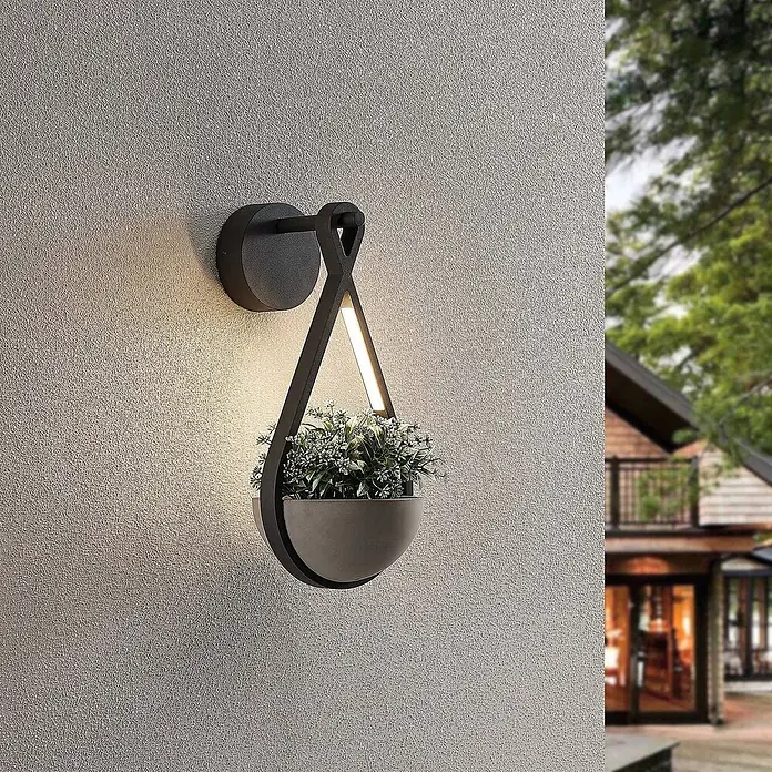 Lucande LED Wandleuchte aussen in dunkelgrau, Aussenlampe Wand -  - Schwarze Außenwandleuchte mit integriertem grauem Pflanzgefäß, beleuchtet, an einer strukturierten Wand montiert.