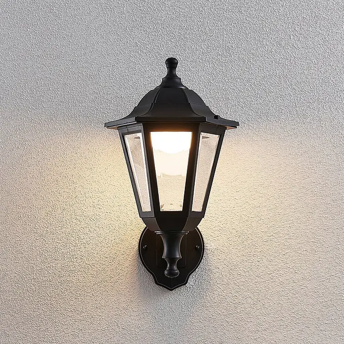 Lindby Außenwandleuchte Iavo - schwarz, schwarz, IP44 - Klassische schwarze Außenwandleuchte mit klarem Glas, leuchtend, an einer strukturierten Wand montiert.