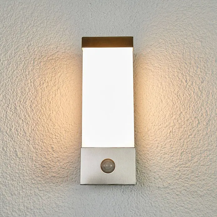 Lindby Außenwandleuchte Severina - alu / grau / zink, IP44 - Rechteckige LED-Wandleuchte mit gebürsteter Metallbasis und integriertem Bewegungssensor, beleuchtet eine strukturierte Wand.