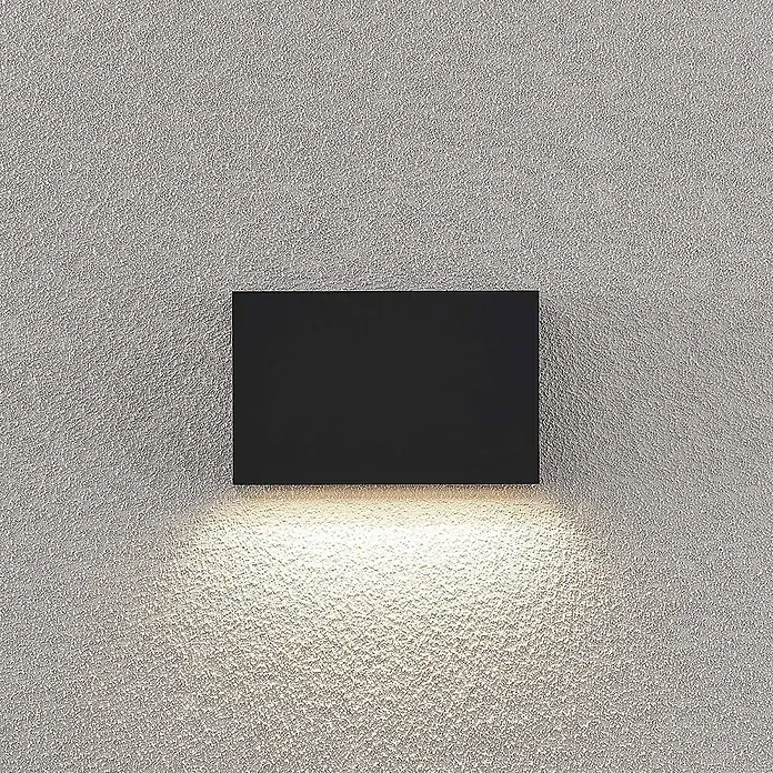 Lindby LED Wandleuchte aussen in dunkelgrau, Aussenlampe Wand -  - Schwarze, rechteckige Wandleuchte, die warmes Licht nach unten auf eine strukturierte Wand wirft.