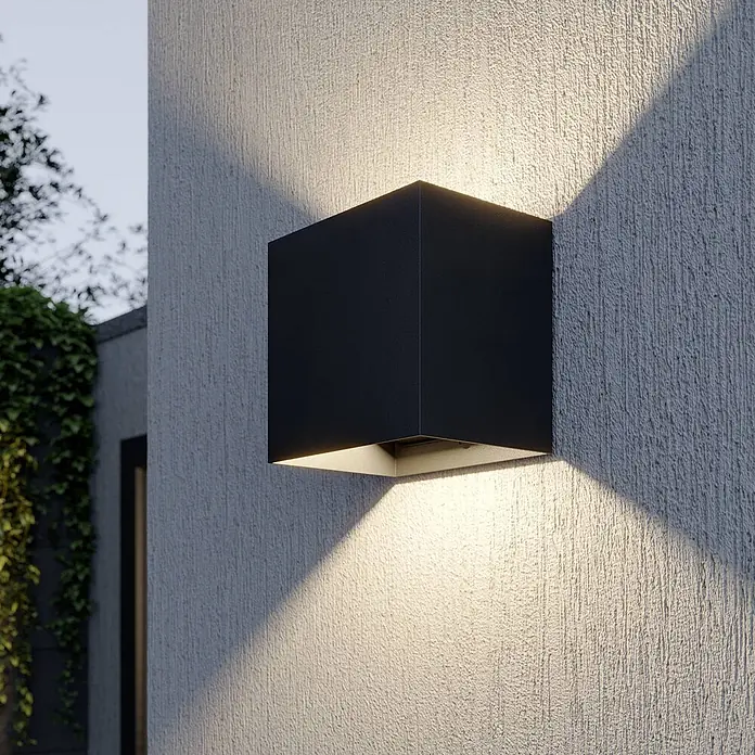 Lucande LED Wandleuchte aussen in dunkelgrau, Aussenlampe Wand -  - Schwarze kubische Außenwandleuchte an strukturierter Wand, wirft Licht nach oben und unten.