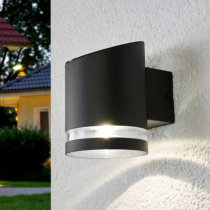 Lindby Solar LED Wandlampe / Wandleuchte außen, 1x 0,5W LED, Downlight -  - Schwarze Außenwandleuchte mit mattiertem Band, beleuchtet eine strukturierte Wand in der Dämmerung.