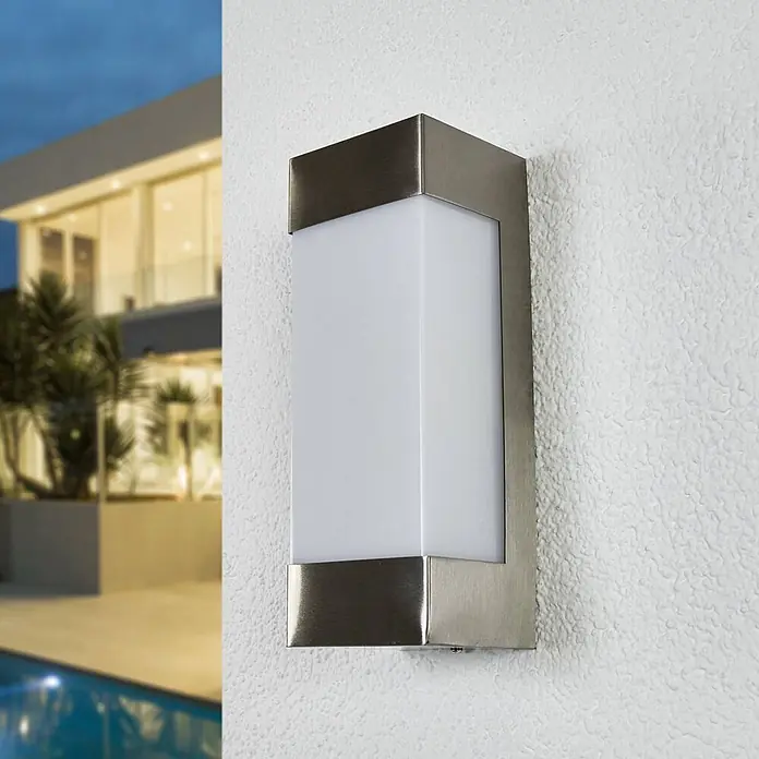 Lindby Edelstahl Wandlampe aussen, 1x 6,5W LED, Außenleuchte -  - Gebürstete Metall-Außenwandleuchte mit mattweißem Diffusor, an strukturierter Wand neben modernem Haus und Pool.