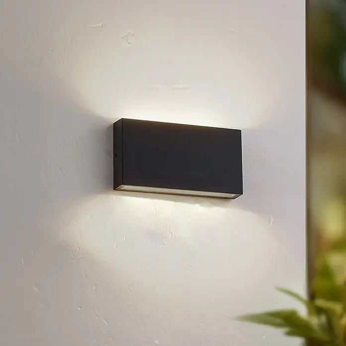 Lindby LED Wandleuchte aussen in schwarz, transparent, up down Aussenlampe -  - Schwarze, rechteckige Wandleuchte mit warmer Auf- und Abwärtsbeleuchtung auf strukturierter Wand.