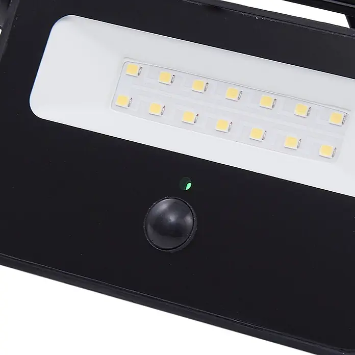 Lindby LED Solar Wandleuchte aussen in schwarz, mit Bewegungsmelder, -  - Schwarzes Gerät mit weißem LED-Panel, grüner Anzeigeleuchte und schwarzem Knopf.