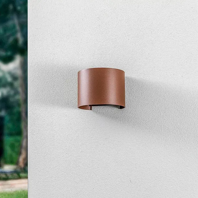 Lindby LED Wandleuchte aussen in rost, up down Aussenlampe Wand -  - Geschwungene kupferfarbene Wandleuchte an einer texturierten weißen Außenwand.