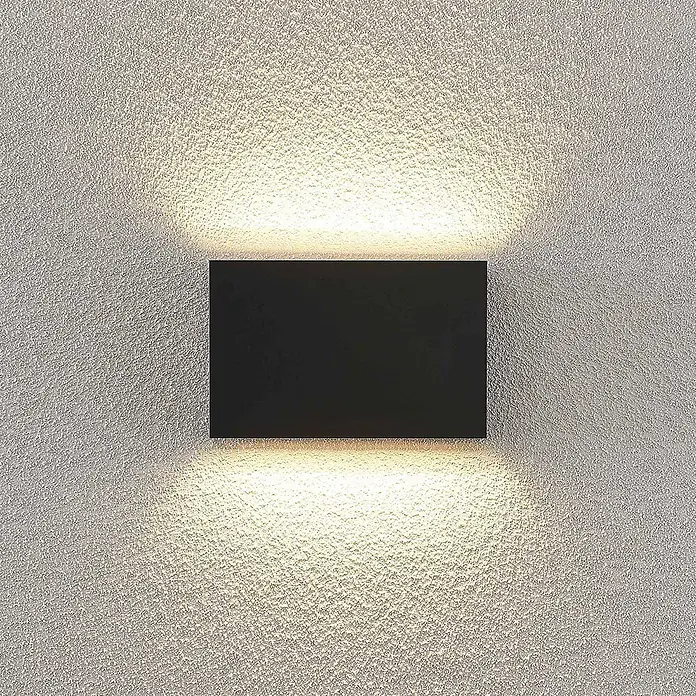 Lindby LED Wandleuchte aussen in dunkelgrau, up down Aussenlampe Wand -  - Schwarze rechteckige Wandleuchte, die eine strukturierte Wand mit Auf-Ab-Beleuchtung beleuchtet.