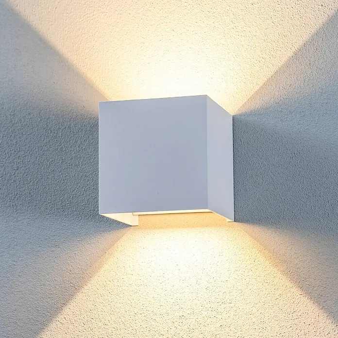 Lindby LED Wandleuchte aussen in weiß, up down Aussenlampe Wand -  - Weiße, würfelförmige Wandleuchte, die eine strukturierte Wand nach oben und unten mit warmem Licht beleuchtet.
