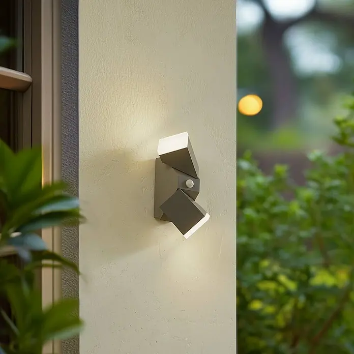 Lindby Außenwandleuchte Sally - alu / grau / zink, alu / grau / zink, IP54 - Moderne graue Außenwandleuchte mit zwei verstellbaren Strahlern und Bewegungsmelder, an einer strukturierten Wand montiert.