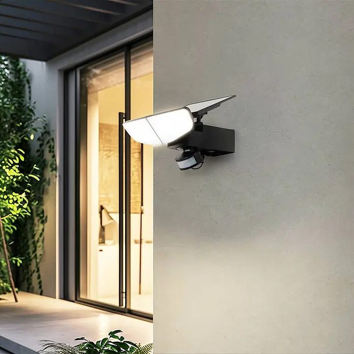 Lindby Außenwandleuchte Naelin - schwarz, schwarz, IP44 - Schwarze solarbetriebene Sicherheitsleuchte mit zwei verstellbaren LED-Paneelen und Bewegungssensor an einer Außenwand.