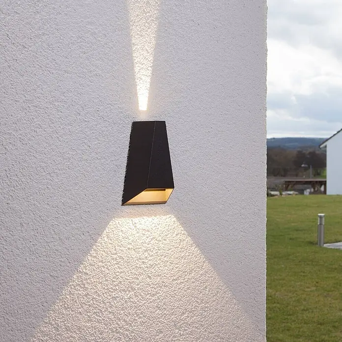 Lucande LED Wandleuchte aussen in anthrazit, Aussenlampe Wand -  - Schwarze, eckige Außenwandleuchte an strukturierter weißer Wand, wirft warmes Licht nach oben und unten.