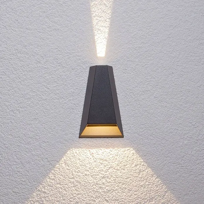 Lucande LED Wandleuchte aussen in anthrazit, Aussenlampe Wand -  - Dunkelgraue, trapezförmige Up-Down-Wandleuchte mit strukturierter Oberfläche, die warmes Licht abstrahlt.