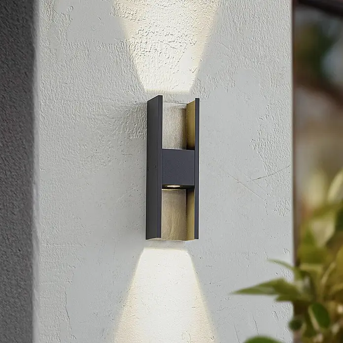 Lucande Außenwandleuchte Lavrin - schwarz, schwarz, IP54 - Dunkelgraue Wandleuchte mit goldener Innenseite, an strukturierter Wand montiert, wirft Licht nach oben und unten.