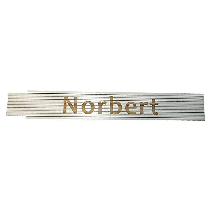 Zollstock - Aufdruck: Norbert, 2 m - Das Bild zeigt eine Namensleiste mit dem Namen Norbert in Holzfarbe, eingebettet in eine silberfarbene Oberfläche. Schlichtes Design für persönliche Beschriftung.