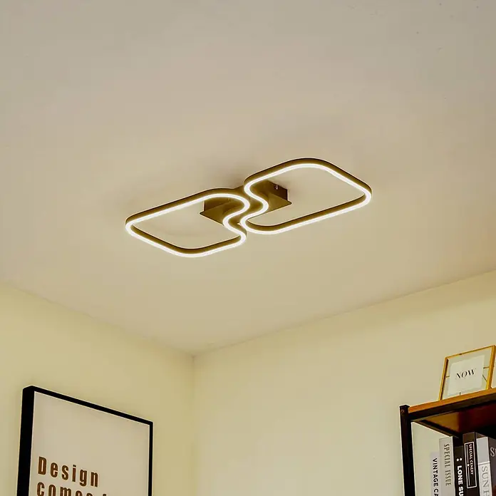 Lucande Deckenleuchte Amiya - schwarz - Moderne geometrische LED-Deckenleuchte mit goldenem Rahmen und weißen Lichtleisten an einer hellen Decke.