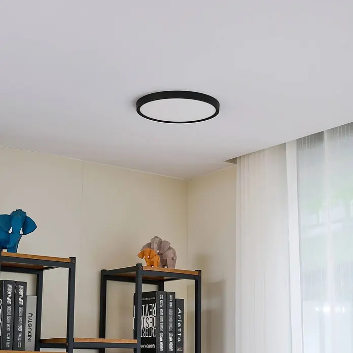 Lindby LED Deckenlampe in schwarz matt, weiß, Deckenleuchte rund -  - Eine minimalistische schwarze runde LED-Deckenleuchte, bündig an einer weißen Decke montiert, beleuchtet einen Raum.