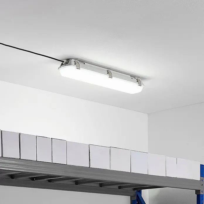 Arcchio LED Feuchtraumleuchte in weiß, Wannenleuchte -  - Lange graue LED-Feuchtraumleuchte an der Decke montiert, beleuchtet einen Lagerbereich mit Regalen.