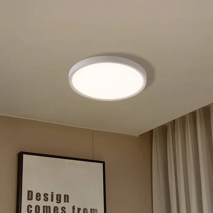Lindby Deckenleuchte Deika - weiß / opal - Eine beleuchtete runde weiße LED-Deckenleuchte, bündig an einer beigen Decke montiert.