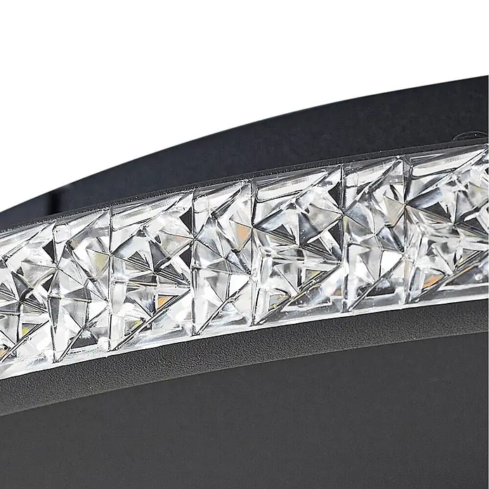 Lindby Deckenleuchte Inessa - schwarz - Nahaufnahme einer modernen Leuchte mit schwarzem, gebogenem Sockel und klarem, facettiertem LED-Streifen.