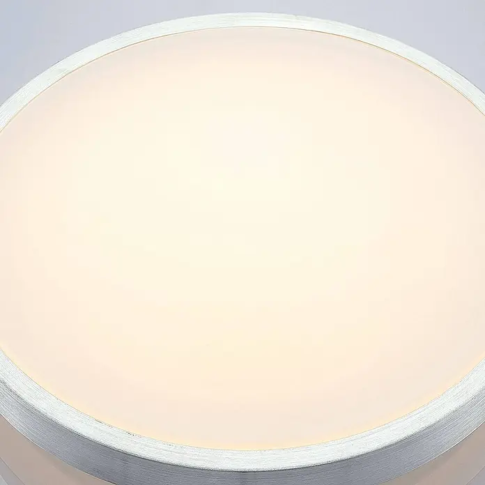 Lindby LED Deckenlampe in aluminium, weiß, Deckenleuchte rund -  - Nahaufnahme einer runden, beleuchteten LED-Deckenleuchte mit weißem Diffusor und strukturiertem, hellgrauem Rahmen.