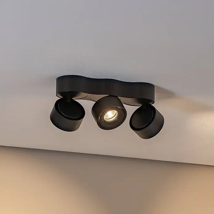Arcchio LED Deckenlampe in schwarz, Deckenleuchte -  - Schwarzer Metall-Deckenstrahler mit drei verstellbaren Köpfen, einer strahlt warmes Licht aus, an einer hellen Decke montiert.