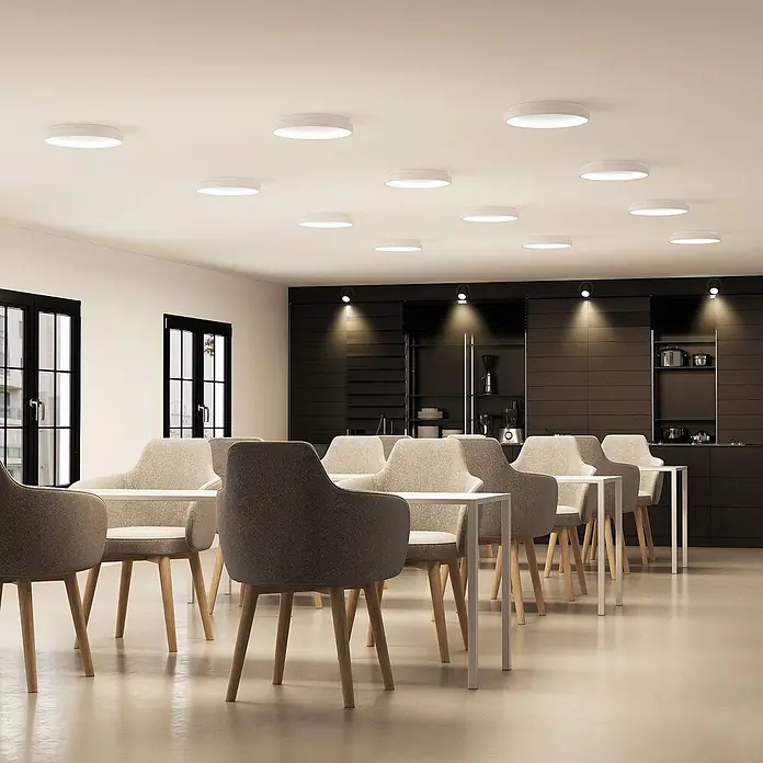 Arcchio LED Deckenlampe in weiß, Deckenleuchte rund -  - Weiße, runde Deckenleuchten erhellen ein modernes Café mit Tischen und Stühlen.