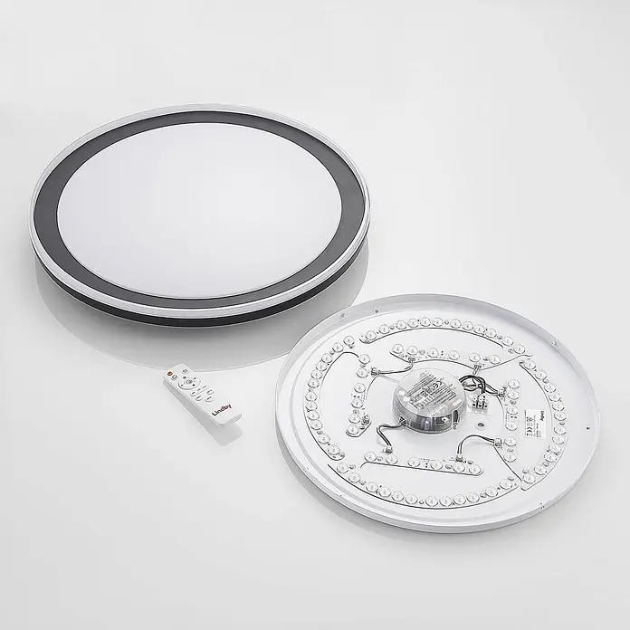 Lindby Deckenleuchte Verdan - schwarz - Zerlegte runde LED-Deckenleuchte mit weißer Abdeckung und grauem Rand, interner LED-Platine und weißer Fernbedienung.