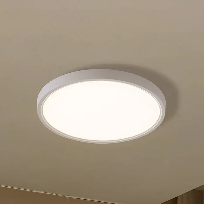 Lindby Deckenleuchte Deika - weiß / opal - Weiße, runde LED-Deckenleuchte mit schlankem Profil, beleuchtet und an einer hellen Decke montiert.