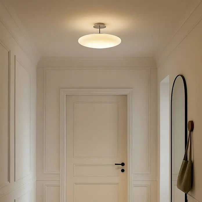 Lindby LED Deckenlampe in weiß, chrom, Deckenleuchte -  - Eine moderne, scheibenförmige Deckenleuchte mit mattweißem Glasdiffusor und silbernem Stiel, die einen Flur beleuchtet.