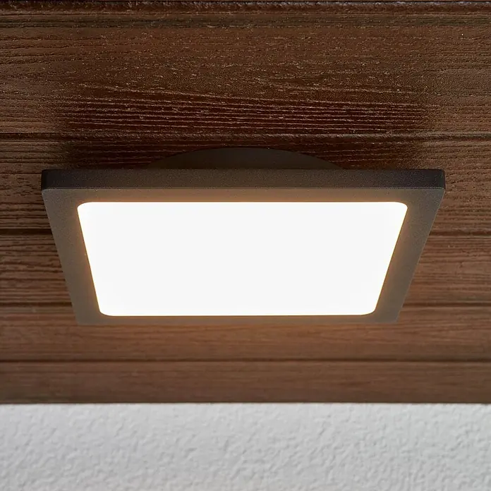 Lucande LED Outdoor Deckenlampe in anthrazit, weiß, Deckenleuchte außen -  - Quadratische, dunkelgraue LED-Außenleuchte, leuchtend, an einer Holzdecke montiert.