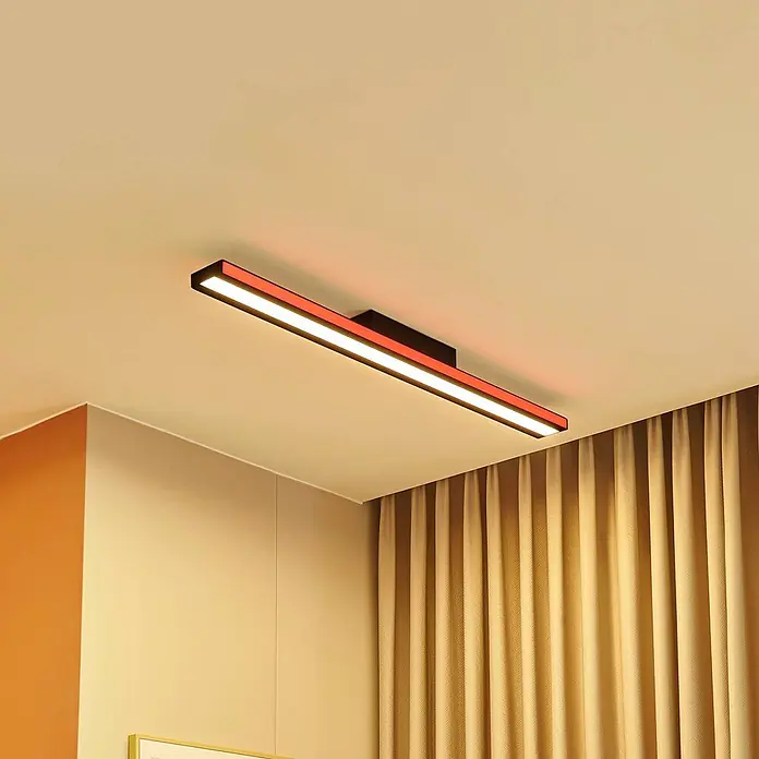 Lucande LED Deckenlampe in schwarz, dimmbar Deckenleuchte -  - Schwarze lineare Deckenleuchte mit weißen und roten LEDs, die eine Zimmerecke beleuchtet.