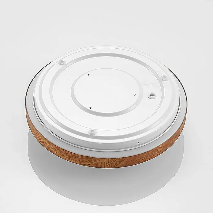 Lindby LED Deckenlampe in holz, weiß, Deckenleuchte rund -  - Unterseite eines runden Geräts, weiße Kunststoffbasis mit Holzmaserungsrand, mit transparenten Füßen und kleinen Öffnungen.