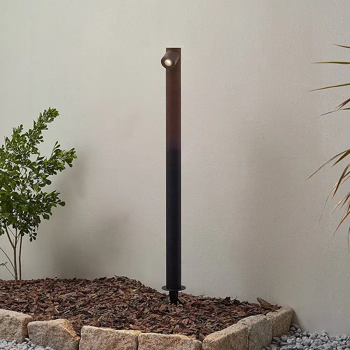 Lindby LED Gartenstrahler mit Erdspieß in anthrazit, Strahler Garten -  - Dunkle Garten-Pollerleuchte beleuchtet ein Landschaftsbeet.