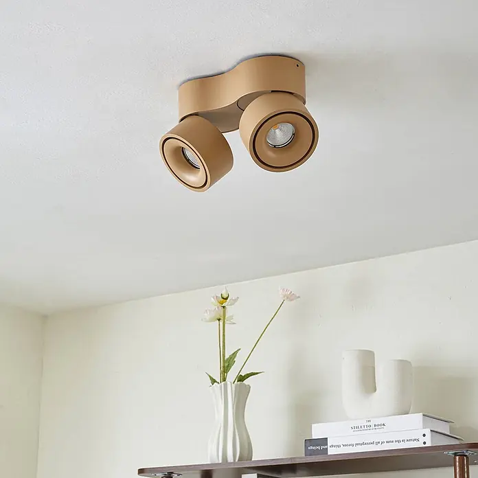 Arcchio LED Deckenlampe in braun, Deckenstrahler -  - Beigefarbener Deckenstrahler mit zwei schwenkbaren Köpfen über einem Regal.
