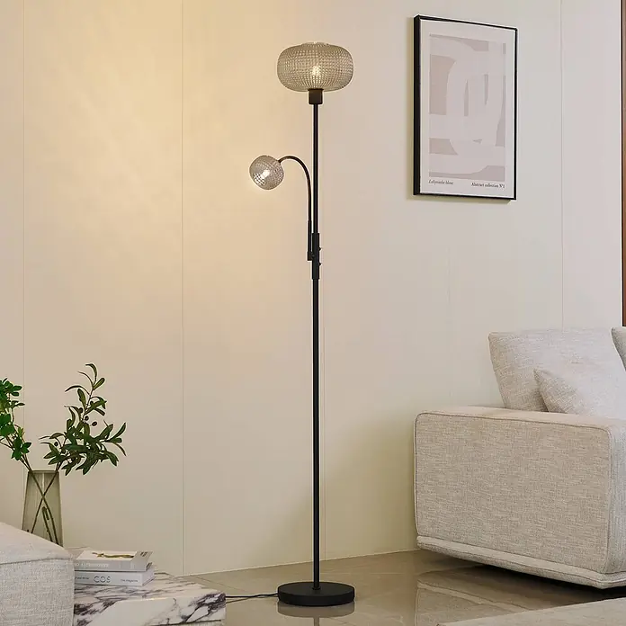 Lindby Stehlampe Leselampe in rauchgrau, schwarz, Stehleuchte -  - Schwarze Stehleuchte mit gemustertem Glasschirm und verstellbarer Leselampe, beleuchtet ein modernes Wohnzimmer.
